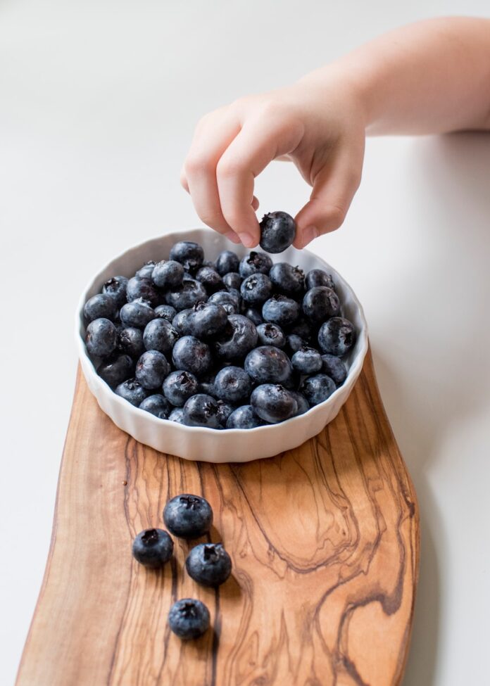 Photo by Davies Designs Studio person holding bowl of black berries