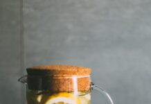 다이어트 성공을 돕는 겨울철 생활 팁 clear glass pitcher filled with sliced lemons on black and white table runner