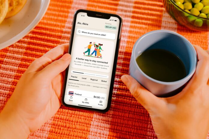 Photo by Growth Airalo Hands holding smartphone with app, coffee cup, and food.