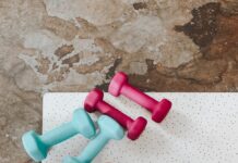 필라테스와 식단: “단백질 쉐이크가 답일까?” 효과를 200% 만드는 영양학 가이드 person holding white liquid filled cup above two pairs of dumbbells