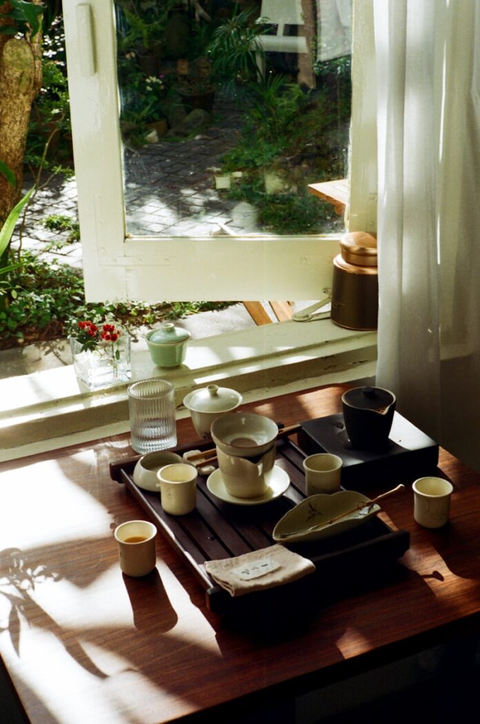 Tea set arranged on a wooden tray by the window.