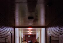 일상에 스며드는 근육 건강, 집에서도 작게 시작하세요 People walk down a dark, brick-walled hallway.