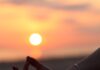 “마음챙김 명상, 바쁜 일상 속 스트레스 해소법으로 주목” A person sitting in a yoga position with the sun setting in the background