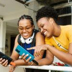 우리 생활에 들어온 AI 건강 관리, 똑똑하게 활용하는 방법은? Two smiling women looking at a smartphone together.